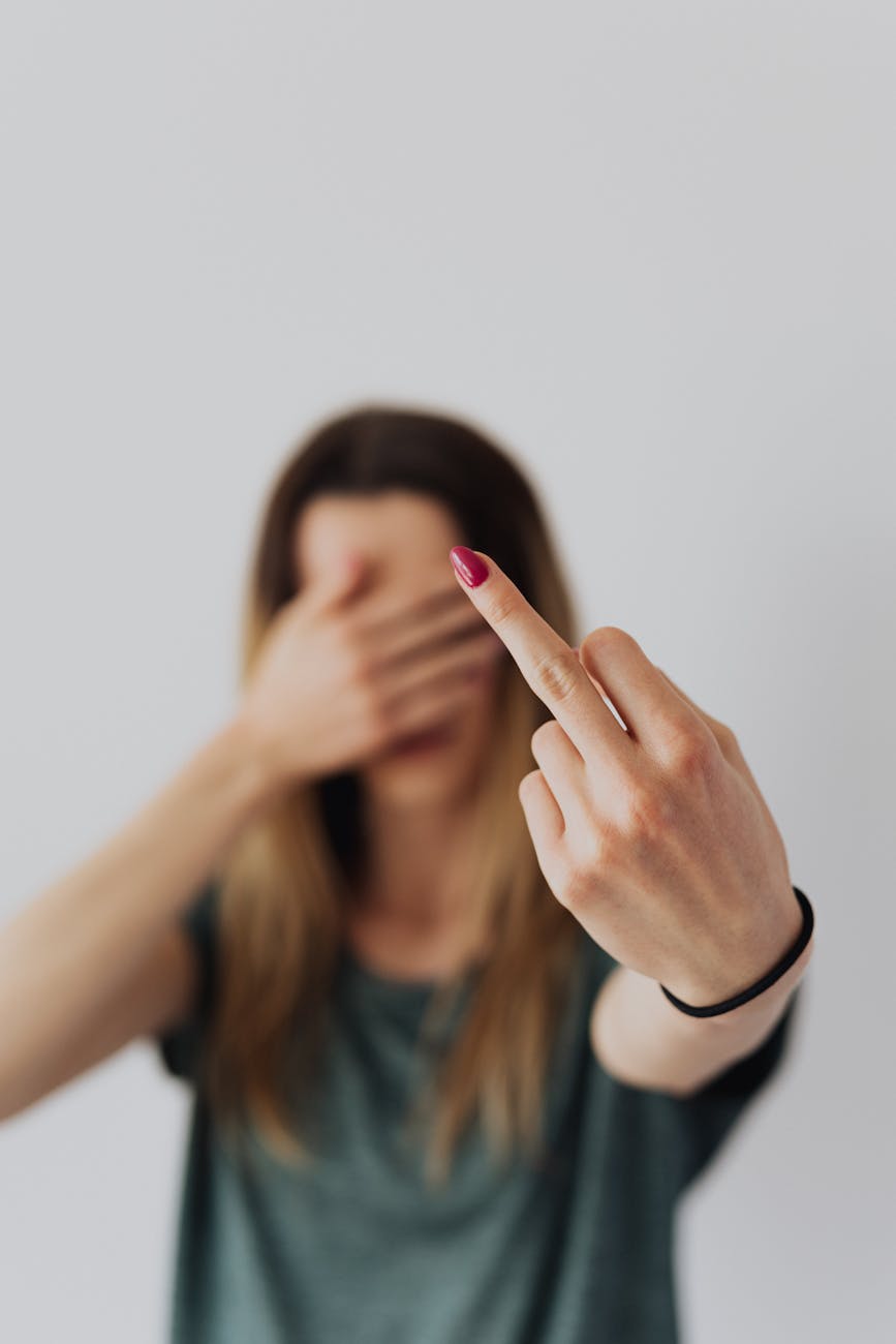hand of woman with pink manicure showing her middle finger up gesture